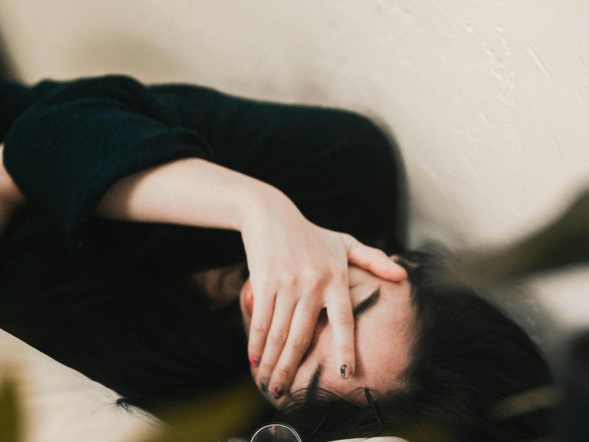 Femme allongée, la main sur le visage, épuisée